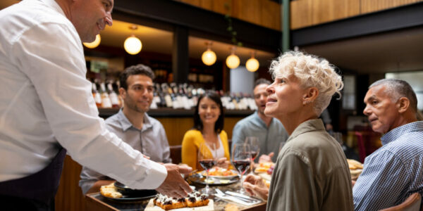 Waiter serving food to a group of friends at a restaurant