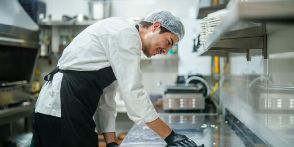 The restaurant chef is wiping down the kitchen counter.