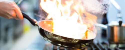 Chef Flambe On Food In Pan On Stove