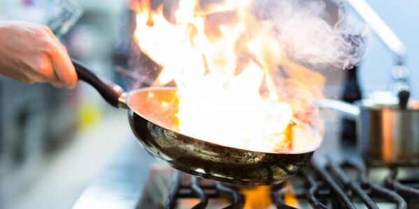 Chef Flambe On Food In Pan On Stove