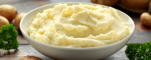 Mashed potatoes in white bowl on wooden rustic table. Healthy food