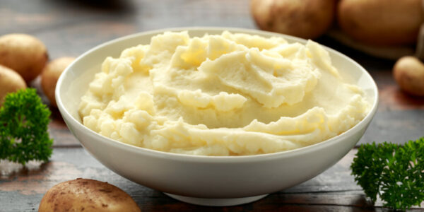 Mashed potatoes in white bowl on wooden rustic table. Healthy food