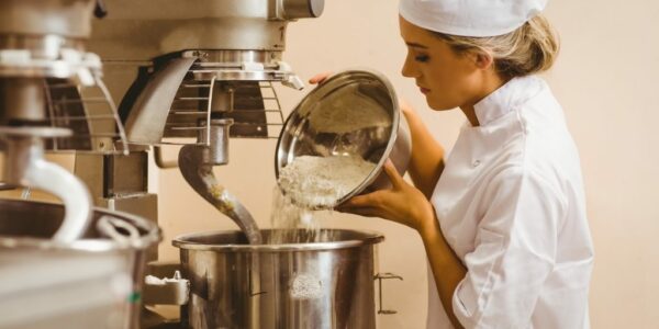 Baker pouring flour into large mixer