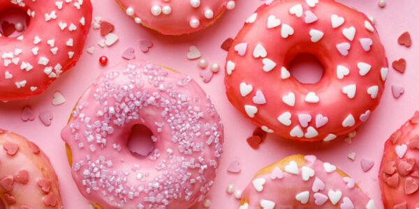 Sweet donuts with pink glaze decorating sprinkles on a pink background