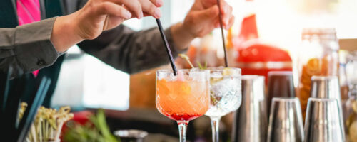 Young bartender making cocktails at bar counter - Barman serving drinks - Work, passion and mixologist concept