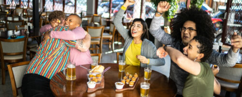 Sports fan friends watching a match and celebrating in a bar