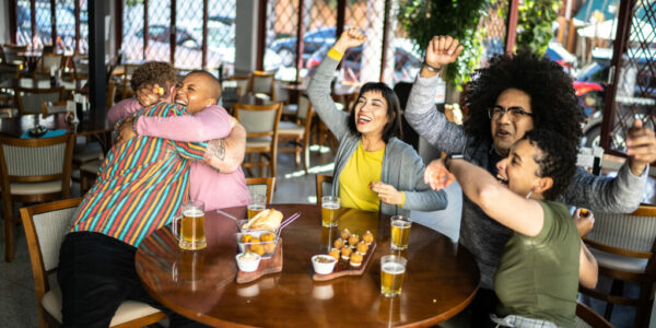 Sports fan friends watching a match and celebrating in a bar