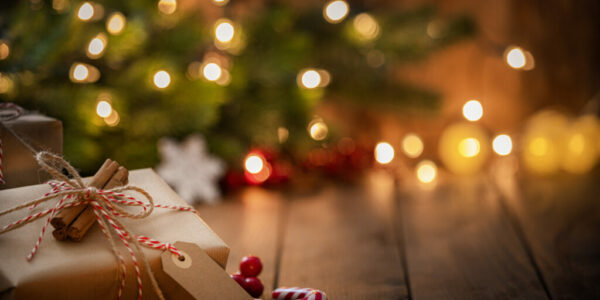 Brown Christmas gift box with a blank tag on rustic wooden table.