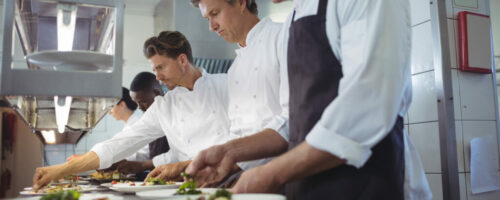 Team of chefs garnishing meal on counter