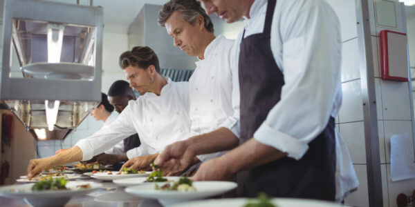 Team of chefs garnishing meal on counter