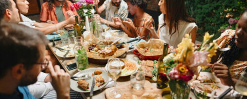 Cheerful friends talking while enjoying dinner at dining table in party