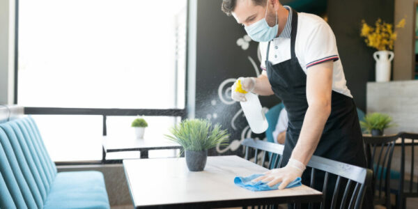 Waiter Spraying Disinfectant On Table