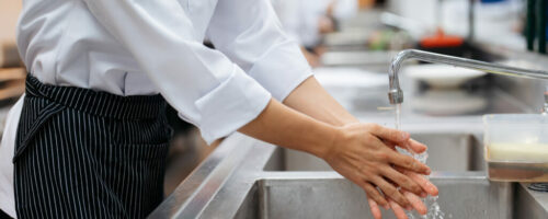 Cropped view of male chef washing hands over sink in restaurant kitchen Cropped view of male chef washing hands over sink in restaurant kitchen