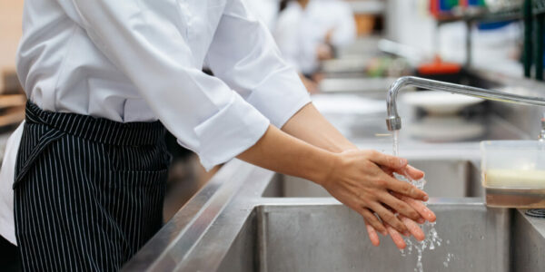 Cropped view of male chef washing hands over sink in restaurant kitchen Cropped view of male chef washing hands over sink in restaurant kitchen