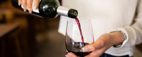 Woman serving red wine in a winery Woman serving red wine in a winery