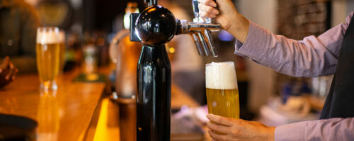 Bartender pouring beer from a tap into glasses Bartender pouring beer from a tap into glasses