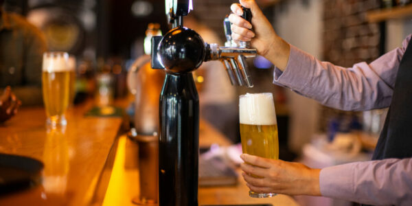 Bartender pouring beer from a tap into glasses Bartender pouring beer from a tap into glasses